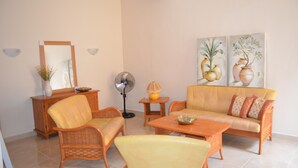 A living room with wicker furniture, a sofa, a fan, and wall-mounted light fixtures. - Summer Haven, with breathtaking views and Private Swimming Pool (Mellieha)