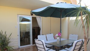 A dining area with a table, chairs, an umbrella, and a potted plant. - IDEAL WITH CHILDREN, WIFI, WHITE SAND BEACH. (Costa Calma, Pajara)