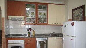 A kitchen with wooden cabinets, a stainless steel dishwasher, and a white refrigerator. - IDEAL WITH CHILDREN, WIFI, WHITE SAND BEACH. (Costa Calma, Pajara)