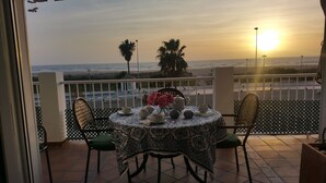 A balcony with a table set for tea, overlooking the sea and palm trees. - APARTMENT CONIL DE LA FRONTERA, GARAGE, WIFI, PROMENADE 5 PERSO (Conil de la Frontera)