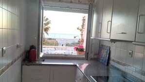 A compact kitchen with a washing machine, a microwave, and a window with a view of the beach. - APARTMENT CONIL DE LA FRONTERA, GARAGE, WIFI, PROMENADE 5 PERSO (Conil de la Frontera)