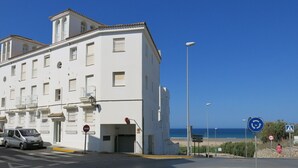 A white building with multiple windows and balconies, a parking area, and a beach view. - APARTMENT CONIL DE LA FRONTERA, GARAGE, WIFI, PROMENADE 5 PERSO (Conil de la Frontera)
