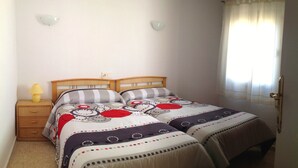 A double bed with a patterned bedspread, a bedside table with a lamp, and a window with curtains. - Levante beachfront vacation with spectacular views and sunny terrace (Benidorm)