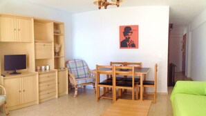 A living room with a TV, wooden furniture, a plaid chair, a table, and a green sofa. - Levante beachfront vacation with spectacular views and sunny terrace (Benidorm)