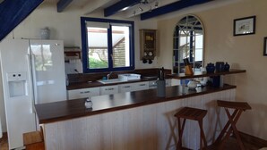 Eine Küche mit einer Holzausziehtheke, weißen Schränken, einer eingebauten Spüle und einem Kühlschrank.
