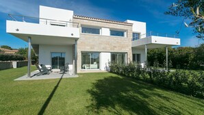 Une maison moderne à deux étages, dotée d’un toit plat, de grandes fenêtres et d’une pelouse bien entretenue.