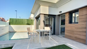A modern house with a swimming pool, a patio with a table and chairs, and a green lawn. - Private pool villa, free wifi, hot tub, roof terrace (Roda)