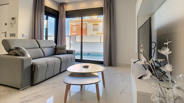 A modern living room with a grey sofa, a small round table, and a large TV on the right. - Private pool villa, free wifi, hot tub, roof terrace (Roda)