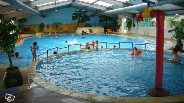 An indoor swimming pool with multiple lanes, a central water slide, and a roofed structure with skylights. - **** SPACIOUS MOBILE HOME 1/8 PERS LES CHARMETTES **** (Les Mathes)