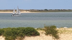 A sailboat on calm waters with a sandy beach and sparse vegetation in the foreground. - **** SPACIOUS MOBILE HOME 1/8 PERS LES CHARMETTES **** (Les Mathes)