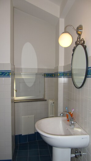 A bathroom with a white sink, a mirror, and a light fixture above the mirror.