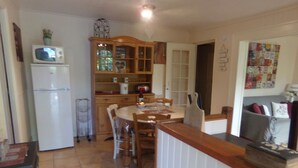 A compact kitchen with a refrigerator, microwave, wooden cabinets, and a dining area with chairs and a table. - Pretty detached house. not overlooked, swimming pool. near Sarlat/Rocamadour (lachapelle haute)