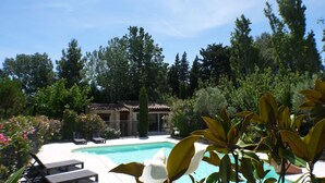 Ein Pool mit Liegestühlen, umgeben von Bäumen und einem Gebäude mit einem Ziegeldach.