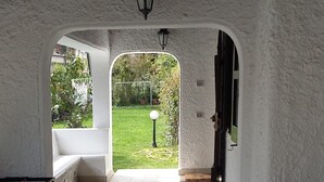 A covered patio area with a foosball table, a sofa, and a view of a garden through an archway. - Detached house on 2 levels near the sea, newly renovated, super-equipped (San Felice Circeo)