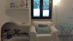 A cozy room with a bed, a small table, and a window with a view of greenery outside. - Detached house on 2 levels near the sea, newly renovated, super-equipped (San Felice Circeo)