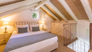 Un dormitorio con una cama grande, dos mesitas de noche con lámparas, un armario y un techo de madera.