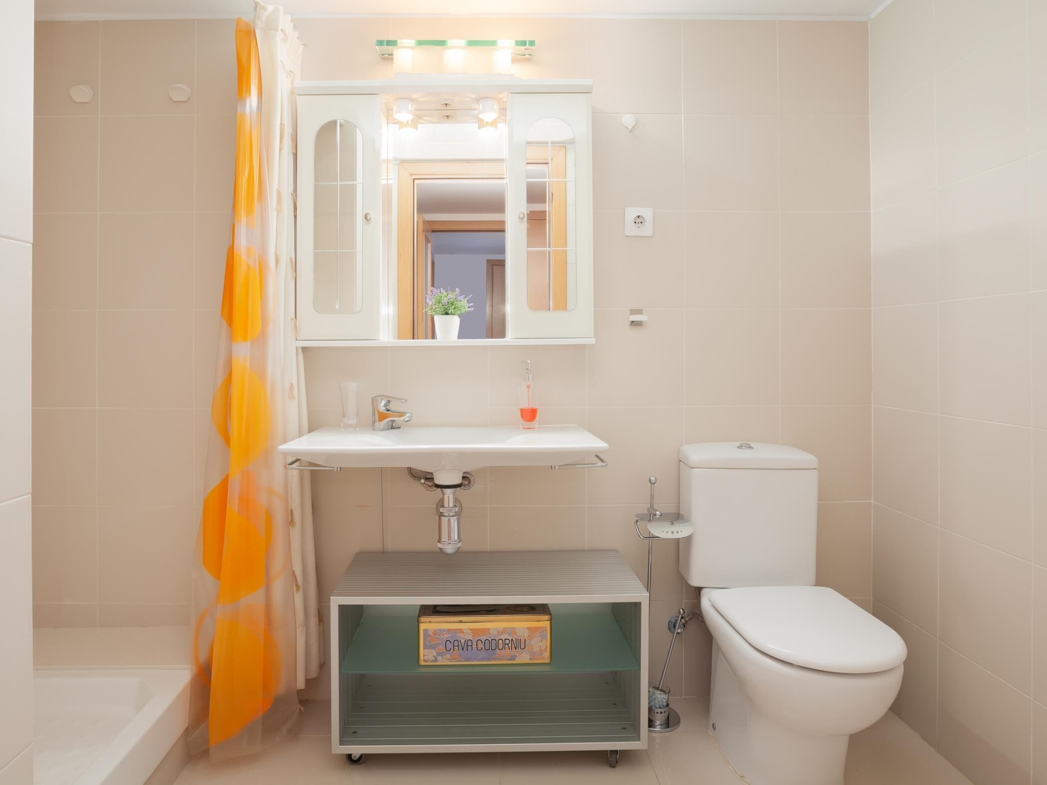 Ein Badezimmer mit Toilette, Waschbecken, Duschvorhang und Waschtischschrank.