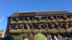 The Dickens Inn with a classic wooden facade, multiple balconies adorned with colorful flower boxes, and a sign indicating the name. - Modern London Tower Bridge apartment (London)