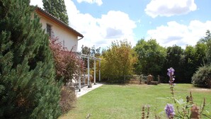 A house with a covered patio, a lawn, and surrounding trees. - Escape from city (Orvieto)