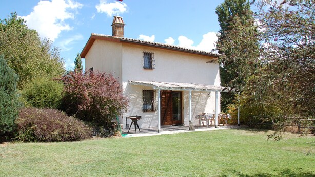 A two-story house with a covered patio, a chimney, and a garden with various plants and a lawn. - Escape from city (Orvieto)