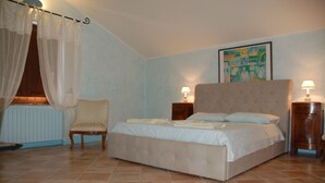 A bedroom with a large bed, two bedside tables with lamps, a chair, and a window with sheer curtains. - Escape from city (Orvieto)