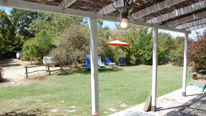 A covered patio area with a table, chairs, and a hanging light fixture. - Escape from city (Orvieto)