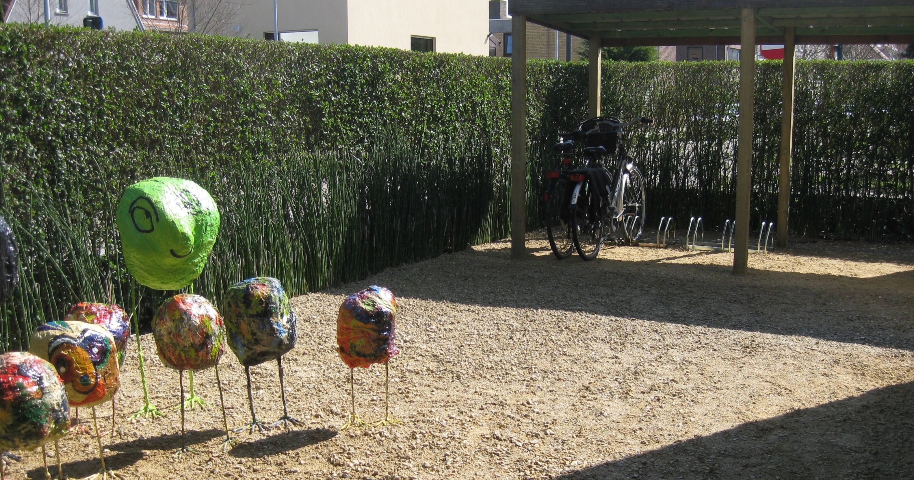 Une zone recouverte de gravier où se trouvent des sculptures colorées, peintes pour ressembler à des oiseaux.