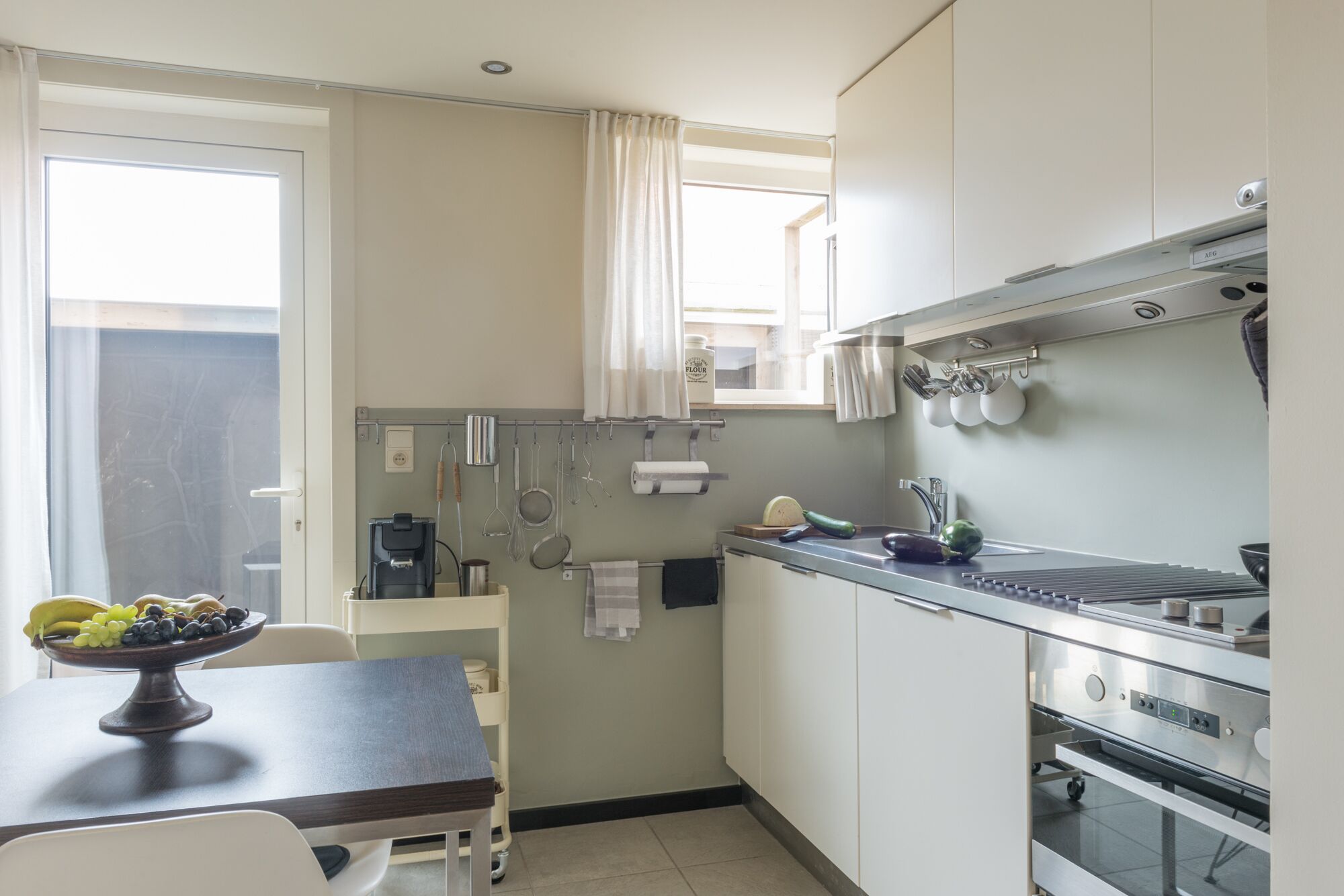 Une cuisine compacte comprenant une table à manger, une machine à café et divers ustensiles accrochés au mur.