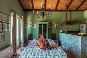 A dining area with a table set for four, surrounded by chairs, a chandelier, and framed pictures on the walls.