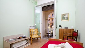 A bedroom with a red bed, a wooden chair, a small table, and a wardrobe. - Villa Mimosa Near Desenzano Old Town Apt 1 Parking, A/C, WiFi, Desenzano Del Garda, Italy (Desenzano Del Garda)