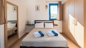 A bedroom with a bed, a mirror, a window, and a wardrobe. - Blue Sea Villa in Gennadi (Gennadi)