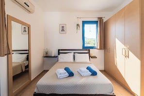 A bedroom with a bed, a mirror, a window, and a wardrobe.