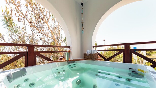 A hot tub with multiple jets, surrounded by wooden railings and a view of trees. - Blue Sea Villa in Gennadi (Gennadi)