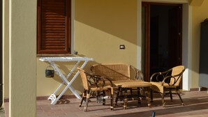 A patio with wicker furniture, a white table, and a door.