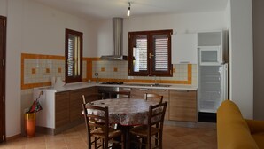 A kitchen with a dining table, chairs, a refrigerator, and a microwave.