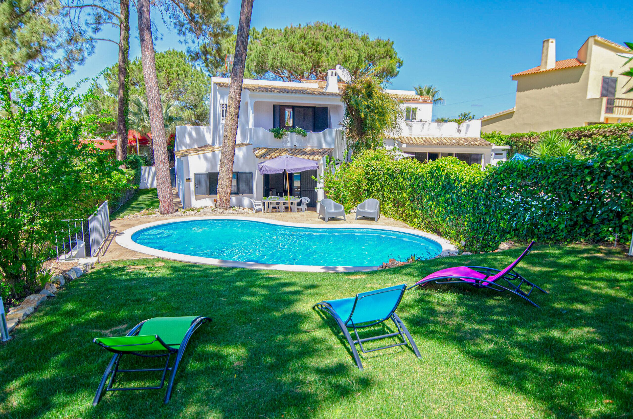 Ein Swimmingpool, umgeben von einer gepflegten Rasenfläche, mit zwei Liegestühlen und einem Patio-Tisch.