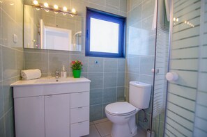 Ein Badezimmer mit weißem Waschbecken, Toilette, einem beleuchteten Spiegel und einem Fenster.