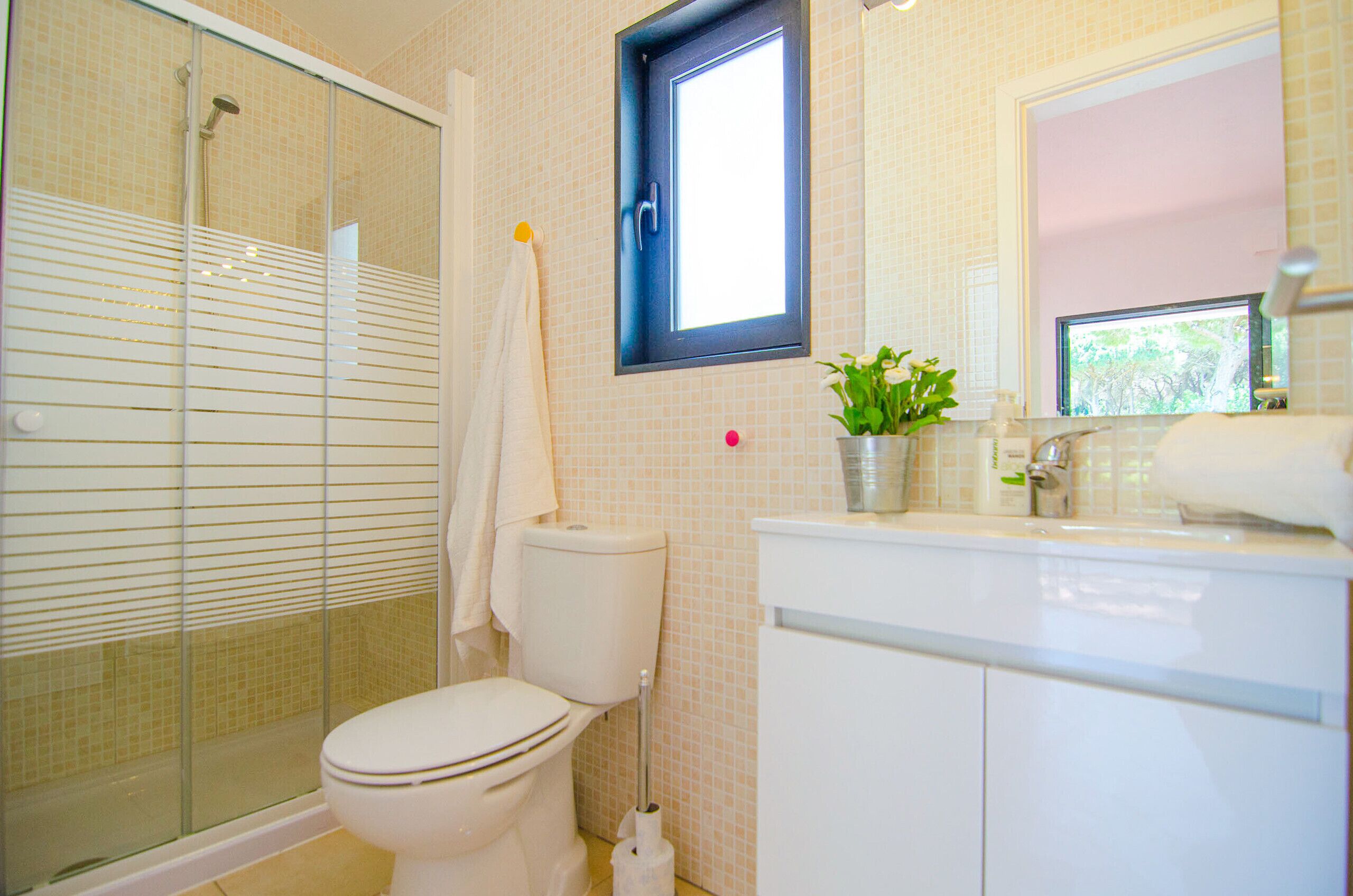 A bathroom with a toilet, a shower, a sink, and a window.