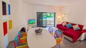 A room with a white table, colorful chairs, a red sofa, and a TV.