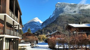 Un village enneigé, avec des bâtiments en bois et une chaîne de montagnes en arrière-plan.