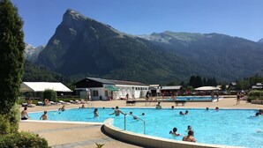Un espace piscine avec une vue imprenable sur les montagnes, entouré de bâtiments et de verdure.