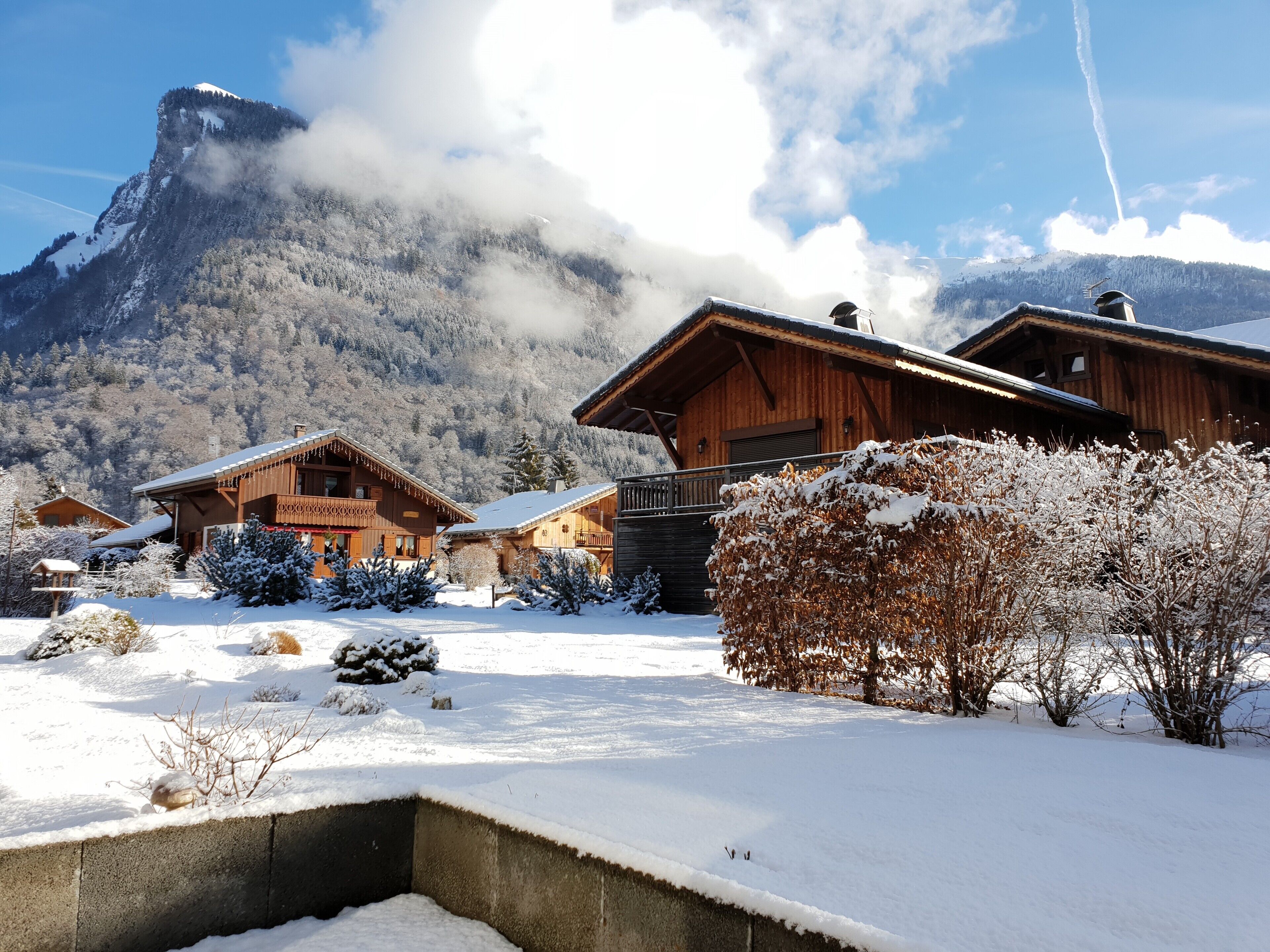 Un chalet en bois, dont le toit est recouvert de neige, entouré d’un paysage enneigé et de montagnes.