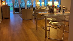 A spacious living area with a wooden floor, a dining table with chairs, a sofa, and a ceiling fan. - Lely Resort Golf Community beautiful condo. (Naples)