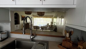 A modern kitchen with white cabinets, a stainless steel sink, and a wooden countertop. - Lely Resort Golf Community beautiful condo. (Naples)