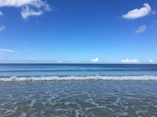 A beach with waves and a clear sky.