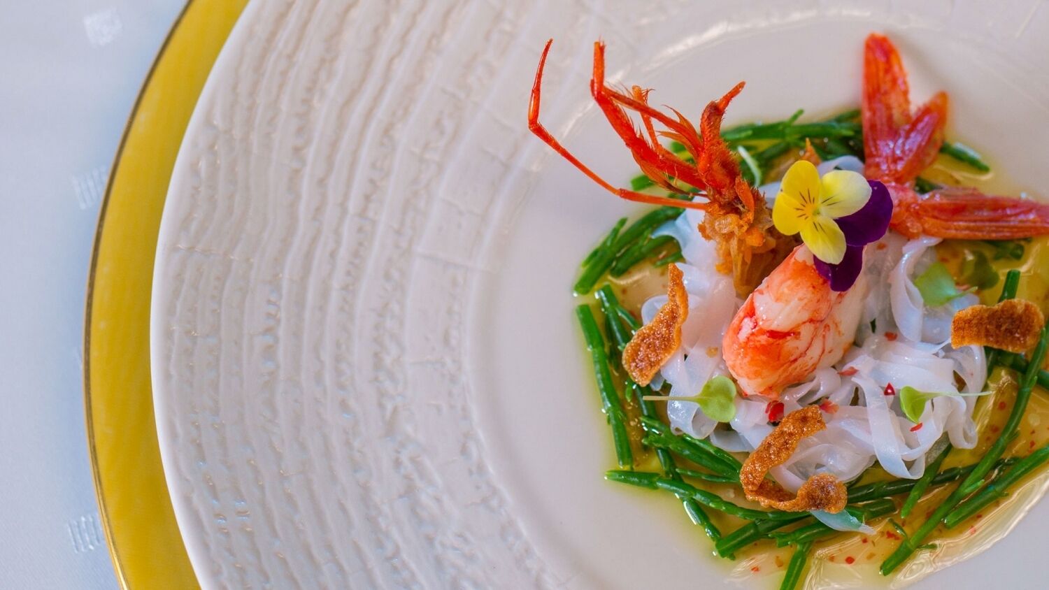 Une assiette de nourriture comprenant des crevettes, des légumes verts et diverses garnitures.
