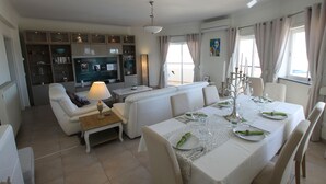 Un salon moderne avec un coin repas, un téléviseur et une cuisine en arrière-plan.