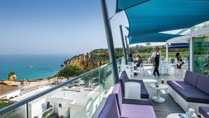 Une terrasse sur le toit avec des sièges extérieurs, une vue dégagée sur la mer et une personne qui se promène.
