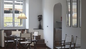 A dining area with a table set for two, chairs, a lamp, and a view through a window. - Delightful two-room apartment in the heart of Genoa. (Genova)