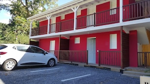 Ein zweistöckiges Gebäude mit roter Fassade und weißem Zierdekor, mit Balkonen und Holzgeländern.